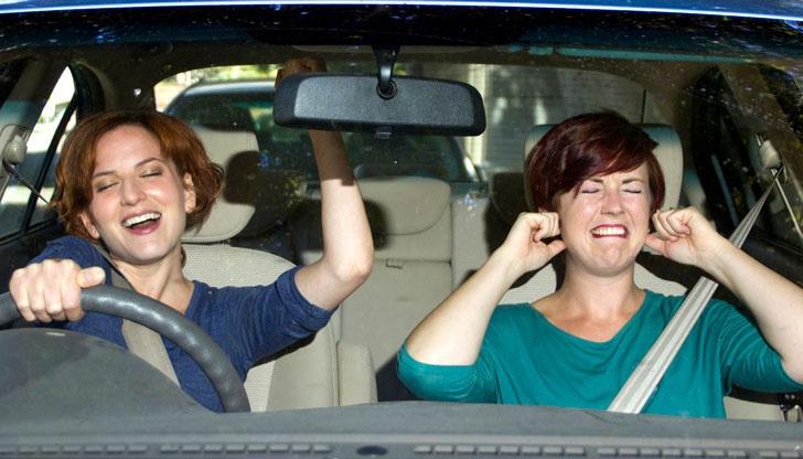 woman singing woman covering her ears in car